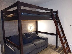 A bunk bed with a ladder, a sofa, and a wall-mounted light fixture. - Charming duplex, mountain view, pets welcome - 8 guests (Tignes)