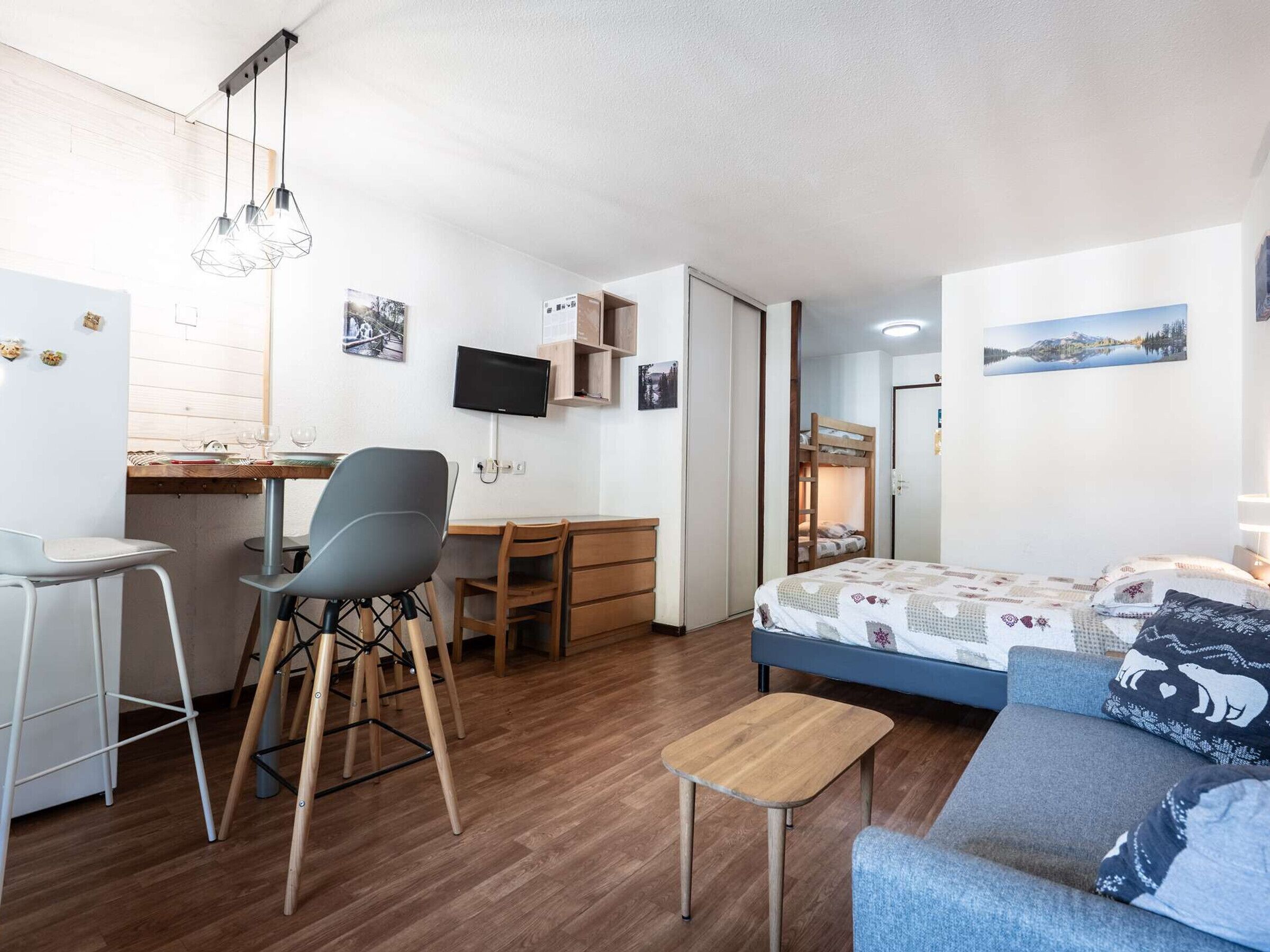 Une pièce de taille modeste comprenant un lit, un bureau, une chaise, une petite table et un téléviseur.