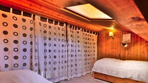 A wooden room with a bed, a window with a view, and a ceiling light. - Studio with mezzanine near village center - 4 guests (Le Grand-Bornand)