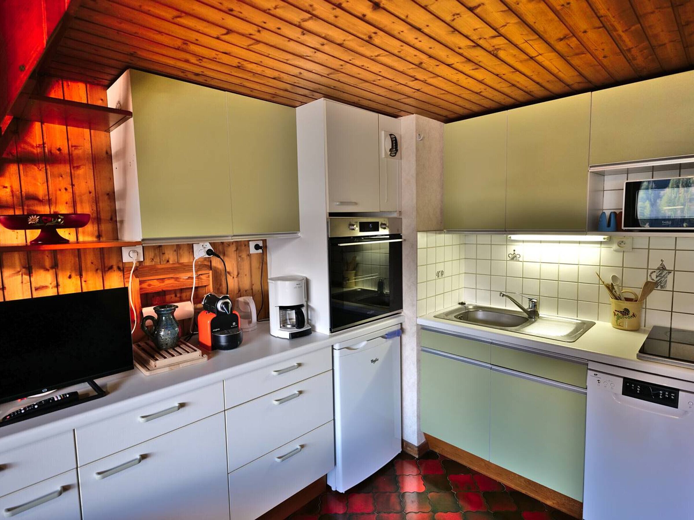 A compact kitchen with white cabinets, a microwave, a coffee maker, and a dishwasher.