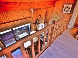 Interior de madera con una escalera de madera, una ventana con vistas a la calle y un escritorio pequeño con una computadora.