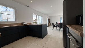 Et moderne køkken med en central ø, et spiseområde med stole, og et køleskab.