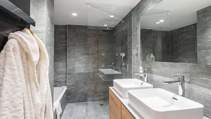 Ein modernes Badezimmer mit Badewanne, zwei Waschbecken und Dusche.
