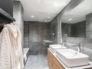 Ein modernes Badezimmer mit Badewanne, zwei Waschbecken und Dusche.