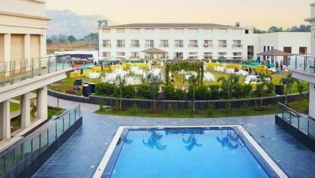 A rooftop swimming pool with a view of a courtyard and buildings. - Estrella The Resort (Karjat)