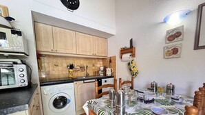 Een kleine keuken met een wasmachine, een magnetron en een broodrooster.