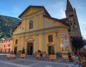 A historic building with a prominent tower, a central entrance, and a courtyard with benches.