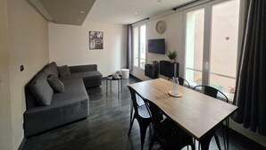 A modern living room with a sofa, a dining table, and a TV.