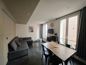 A modern living room with a sofa, a dining table, and a TV. - Apartment 2 rooms 4 persons St Étienne de tinée mountain ski touring (Saint-Étienne-de-Tinée)