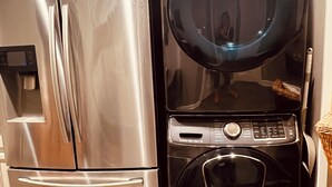 A stainless steel refrigerator and a black washing machine in a kitchen with white cabinetry. - Dragonfly Inn II 
Fabulous 2BR 1BA modern downtown apt  walk to everything (Winchester)