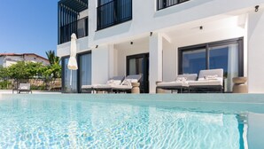 Ein modernes Hotel mit Pool, Liegestühlen und blauem Himmel.