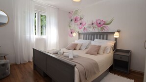 Ein Schlafzimmer mit einem Bett, Nachttischen, einem Spiegel und einem Fenster mit Vorhängen.
