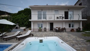 Ein zweistöckiges Haus mit Swimmingpool, Sitzgelegenheiten im Freien und einer Grillzone.