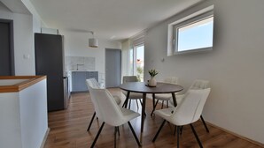 Ein Essbereich mit einem runden Tisch, vier Stühlen, einer Blumenvase und Blick auf einen Balkon.