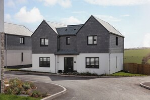 A modern two-story house with a symmetrical facade, a central entrance, and a driveway leading to the front door. - Polview (Newquay)