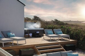 A deck with lounge chairs and a hot tub, surrounded by vegetation and a clear sky. - Polview (Newquay)
