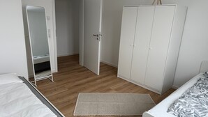 Et soveværelse med seng, garderobeskab, spejl og natbord.