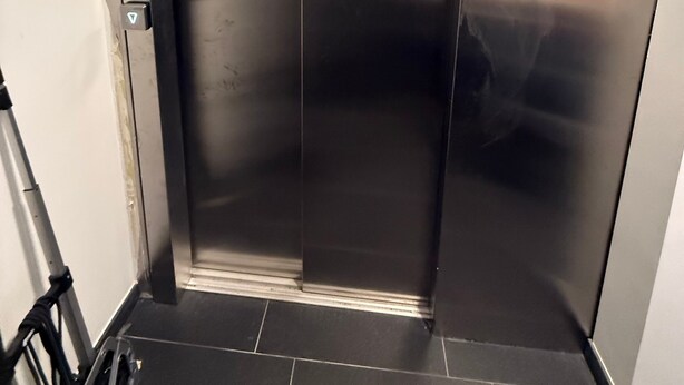 En metal dør til elevator med kontrolpanel på venstre side.