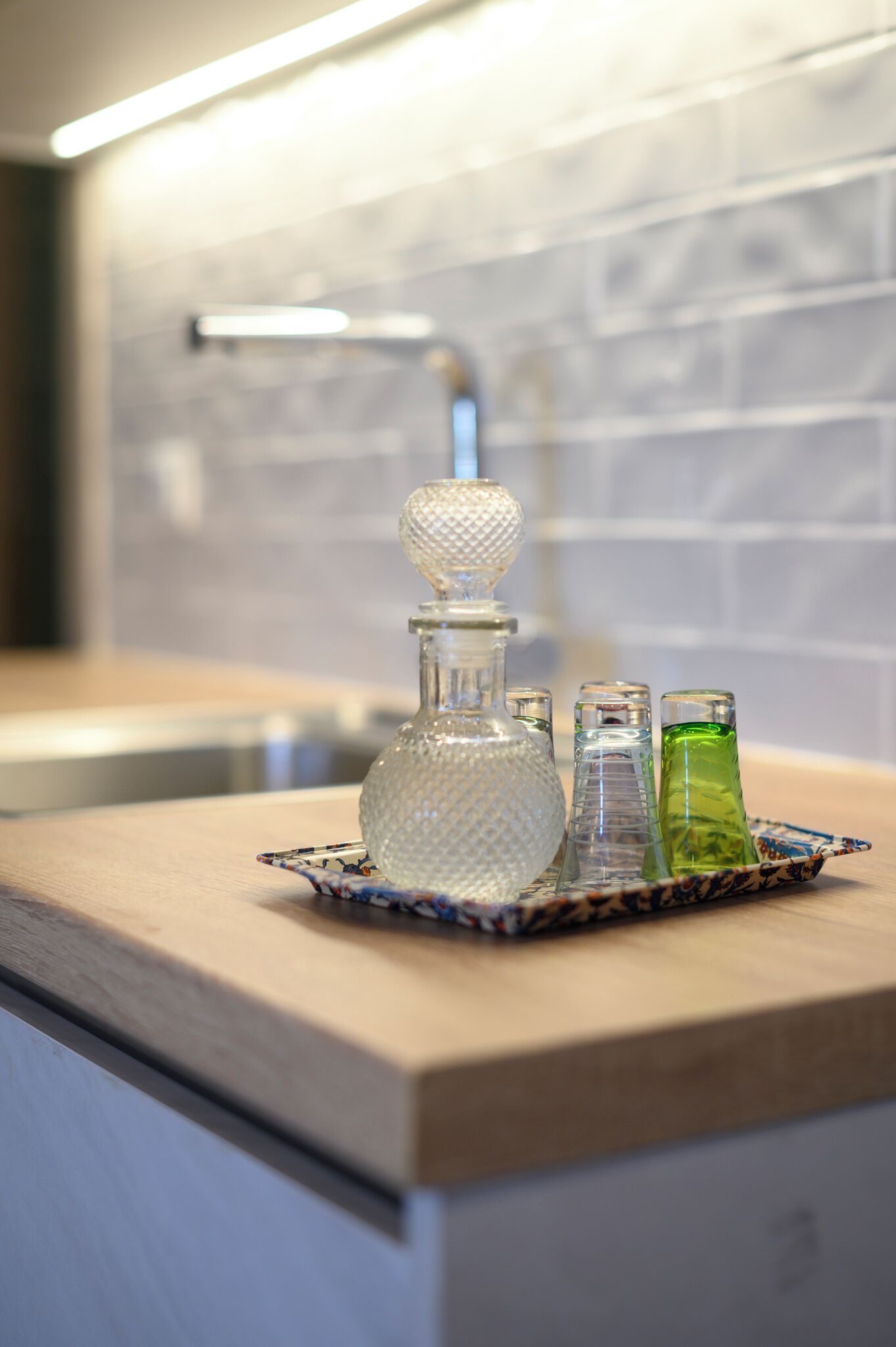 A kitchen counter with a glass decanter, two glass bottles, and a tray.