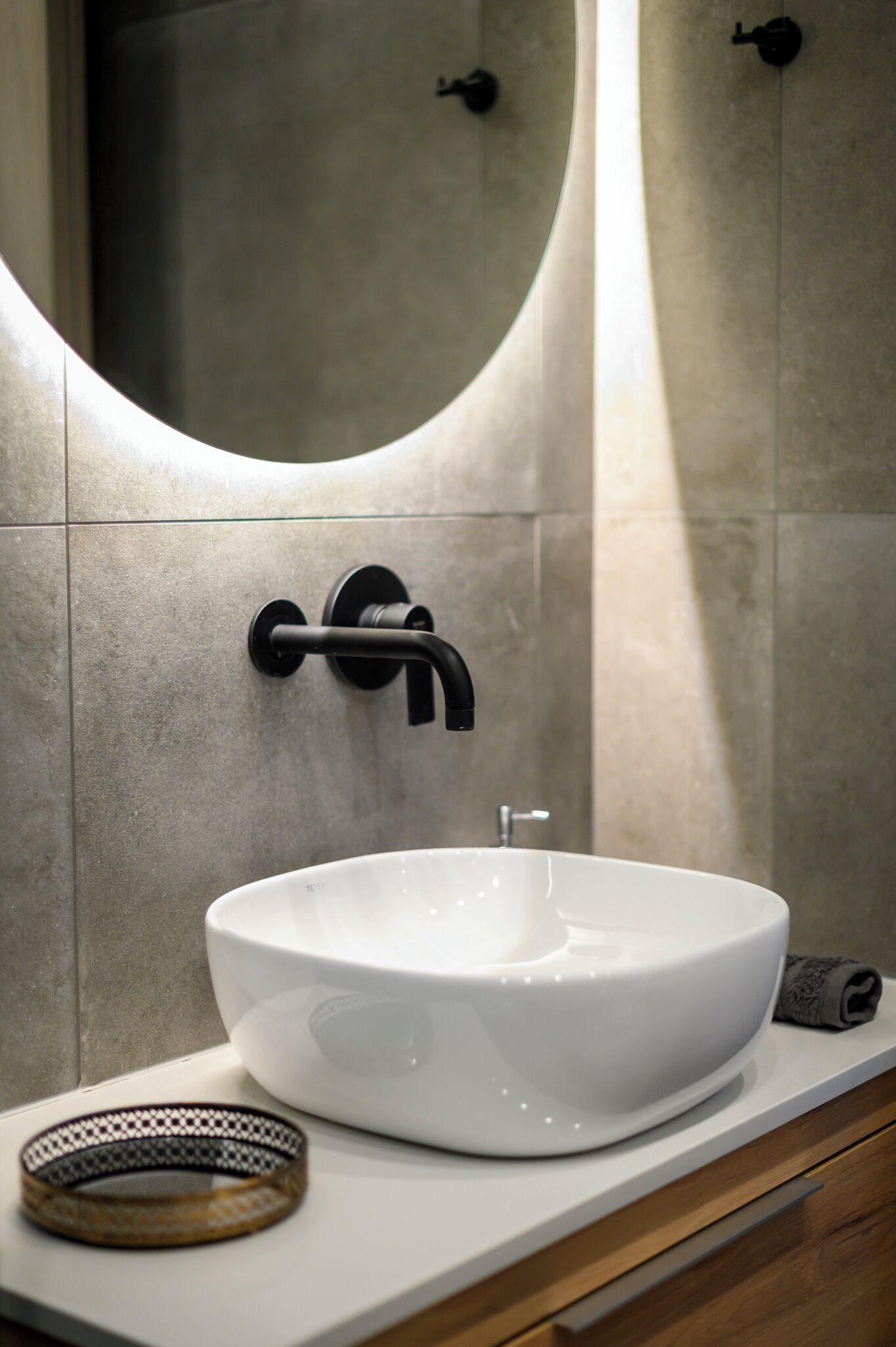 A modern bathroom with a white vessel sink, a black faucet, and a towel on the counter.