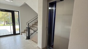 A spacious hallway with a modern elevator and a staircase leading to an outdoor area. - Cozy vacation rental in the Allgäu region—perfect for families and couples (Sontheim)