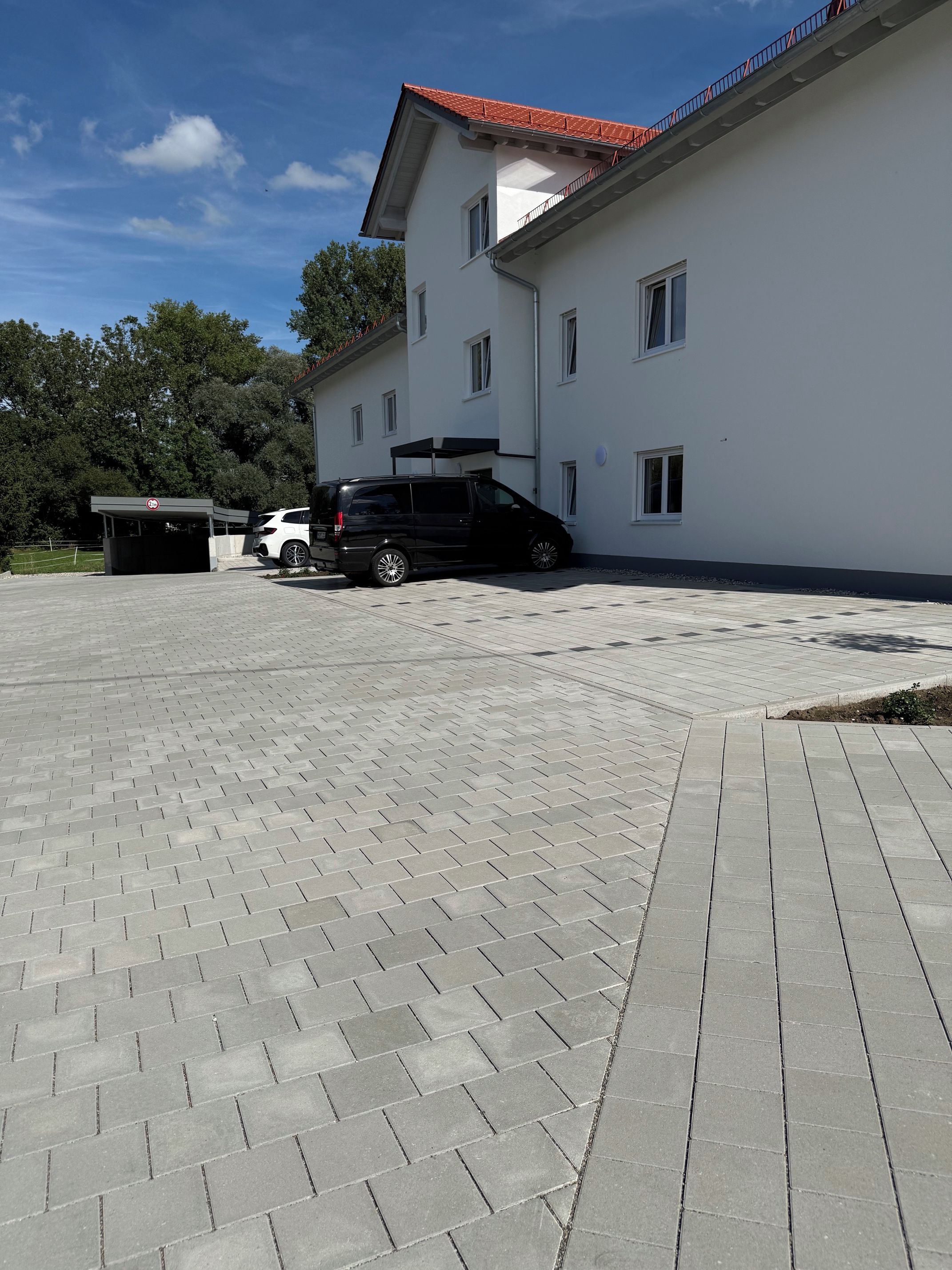Ein Gebäude mit befestigter Auffahrt und überdachtem Parkbereich.