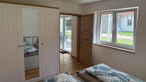 A bedroom with a bed, a wardrobe, a window, and a door leading to a balcony. - Cozy vacation rental in the Allgäu region—perfect for families and couples (Sontheim)