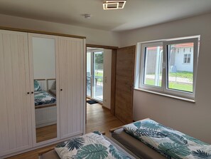 Ein Schlafzimmer mit einem Bett, einem Kleiderschrank, einem Fenster und einer Tür, die auf einen Balkon führt.