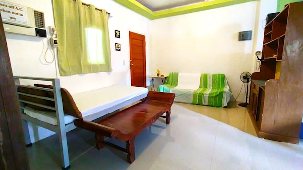 A room with a bunk bed, a sofa, a small table, and a fan.
