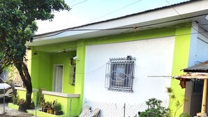 A residential building with a green facade, a white door, and a window with a metal grille.