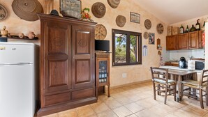 Una cocina con armarios de madera, un refrigerador, una mesa de comedor con sillas y platos decorativos en la pared.