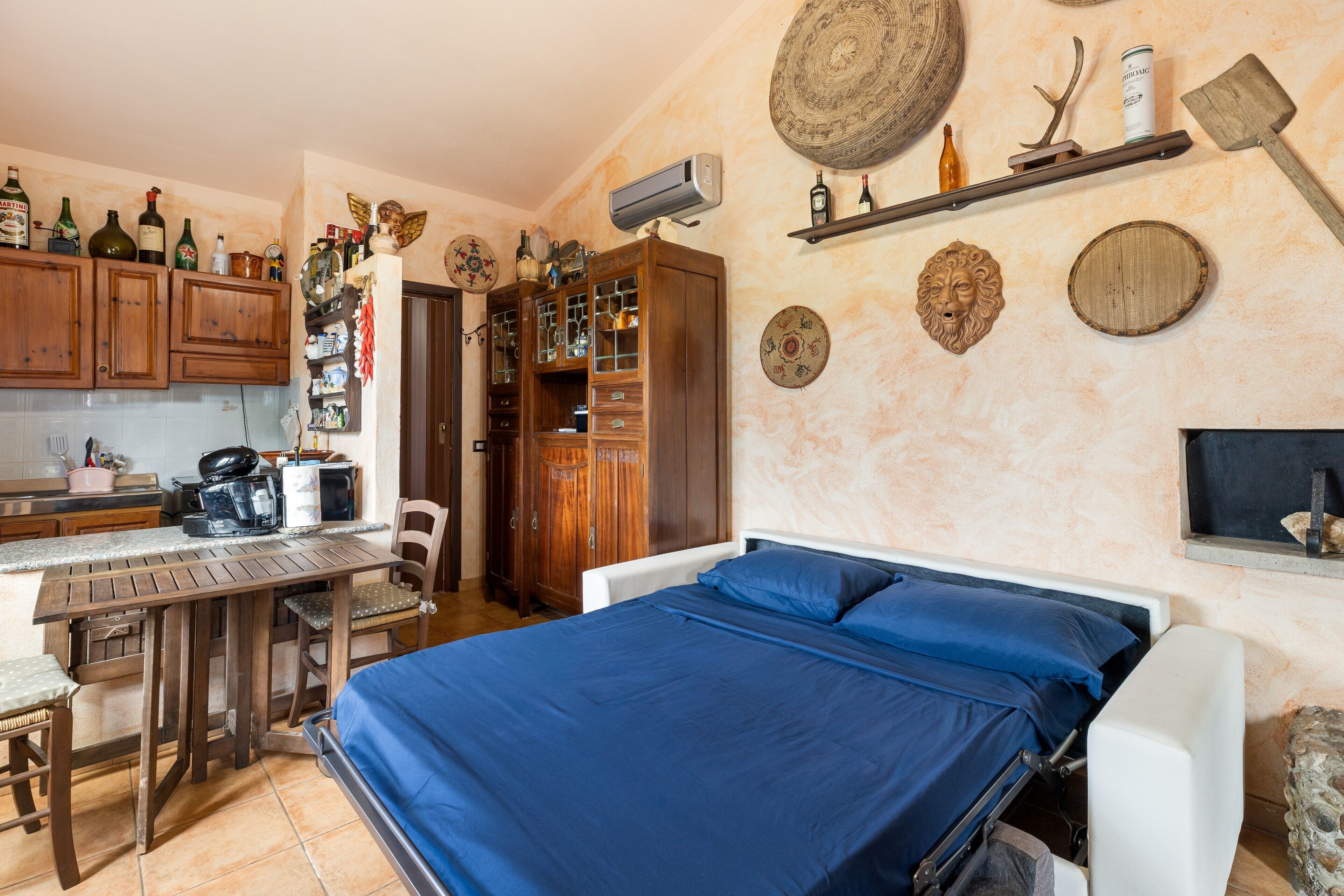 Une chambre avec un lit, un bureau et un coin cuisine.