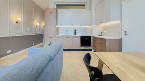 A modern kitchen with built-in appliances, a dining area with a wooden table and chairs, and a sofa. - AS HOME Rynek 265 (Wrocław)