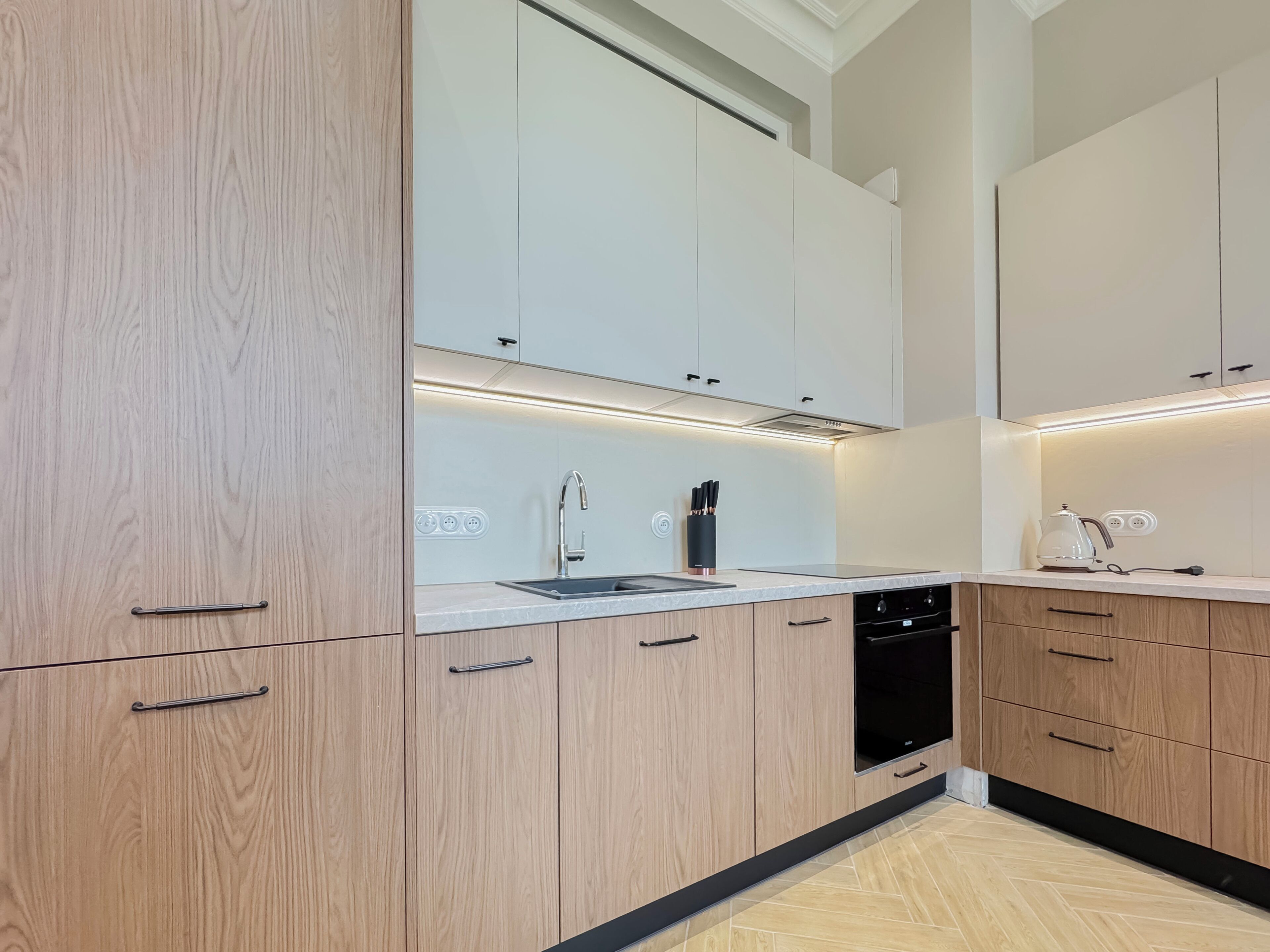 Una cocina moderna con armarios de madera, lavavajillas integrado e iluminación debajo de los armarios.