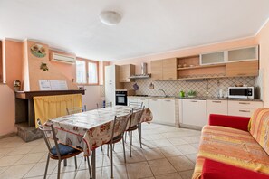 Een kleine keuken met een eettafel, stoelen, een bank en een magnetron.