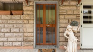 A stone building with a wooden door, a statue, and a potted plant. - Apartment 'Casa Anna - Bosa' with Air Conditioning (Bosa)