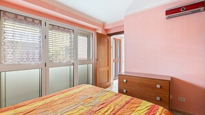 A bedroom with a bed, a wooden dresser, a window with blinds, and a door leading to another room. - Apartment 'Casa Anna - Bosa' with Air Conditioning (Bosa)