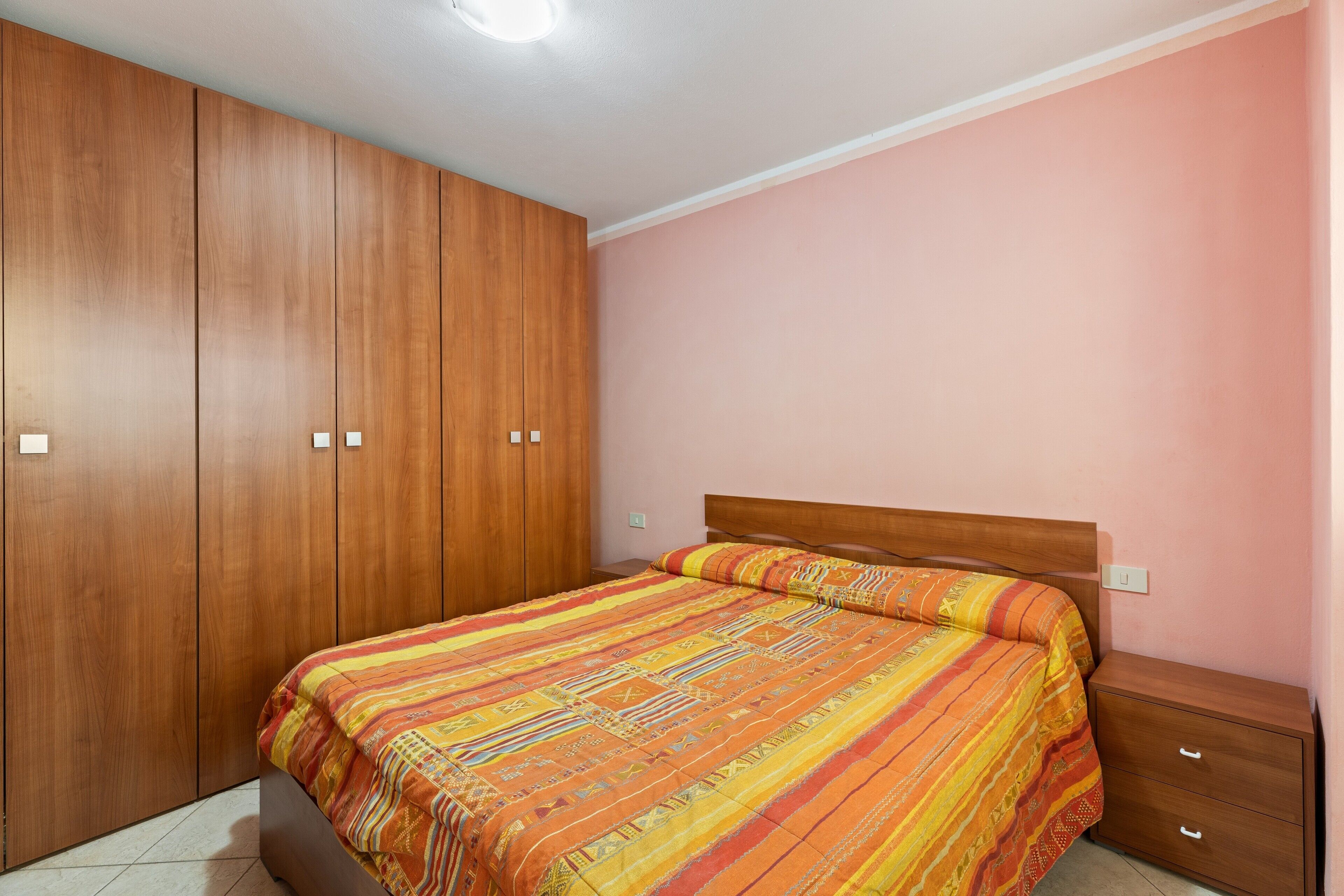Une chambre à coucher avec un lit, une armoire en bois et une table de chevet.