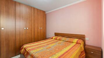 Une chambre à coucher avec un lit, une armoire en bois et une table de chevet.