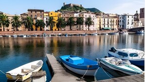 A waterfront marina with boats docked, a historic hilltop fortress, and colorful buildings along the shore. - Apartment 'Casa Anna - Bosa' with Air Conditioning (Bosa)
