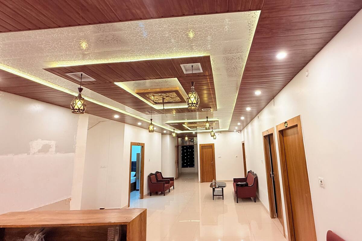 A modern hotel lobby with a wooden ceiling, recessed lighting, and a central seating area.