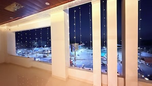 A room with large windows overlooking a parking area at night.