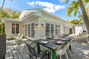 Eine überdachte Terrasse mit Esstisch, umgeben von Stühlen und einer Holzterrasse.