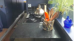 Cozinha com fogão a gás, uma panela e um suporte de utensílios com utensílios de madeira.