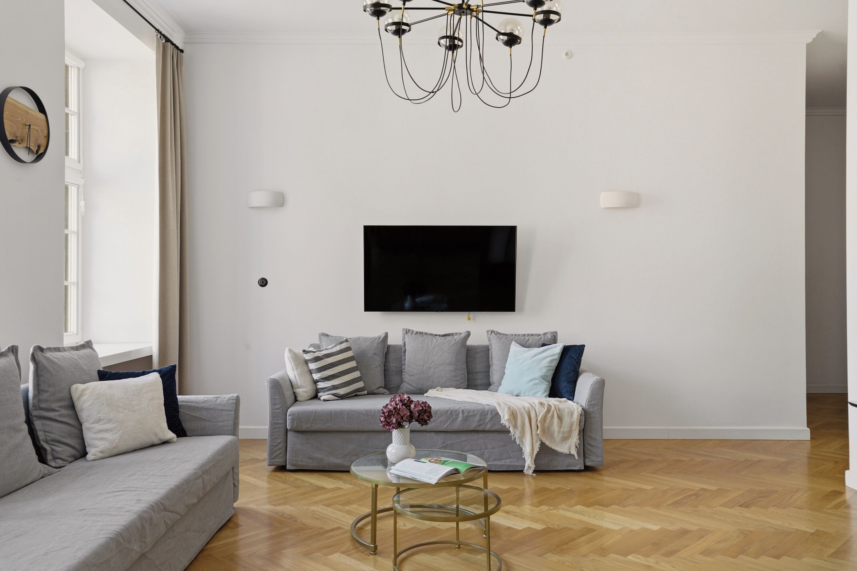 A modern living room with a grey sofa, a coffee table, and a TV mounted on the wall.