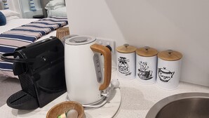 Et tekøkken med kaffemaskine, elkedel og tre kaffekapsler.