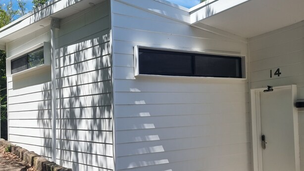 En moderne bygning med hvid facade, en garageport og en dør med nummer 14.