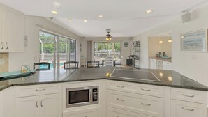 A spacious kitchen with a central island, large windows, and a view of the outdoors. - Just Breathe | Your Private Canal front Escape with Pool & Dock on Siesta Key (Siesta Key)