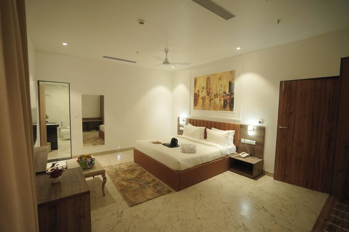 A modern bedroom with a large bed, bedside tables, a mirror, and a painting on the wall.