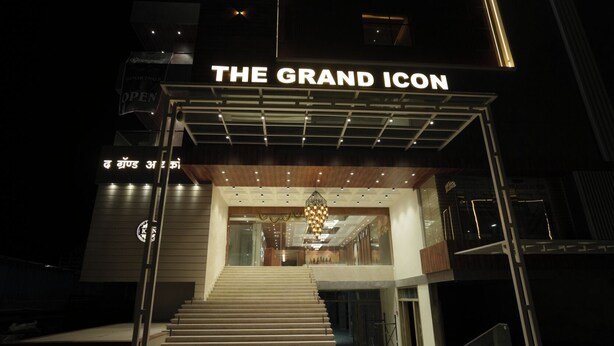 Una entrada de hotel con un gran cartel distintivo, una escalera que conduce al vestíbulo y una decoración interior moderna.